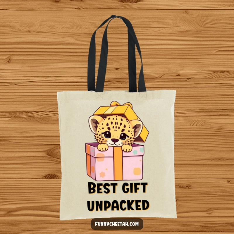 Funny tote bag showcasing a cheetah cub peeking playfully from a colorful gift box, ideal for carrying essentials with a touch of joyful mystery.